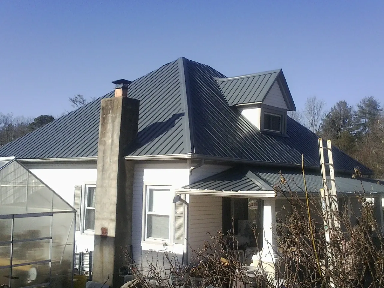 Dark blue standing seam metal roof on a white farmhouse with dormer — Slate & Tile Roof Repair by Roofing Brothers in Ariel