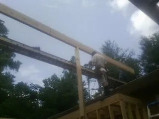 Carpenter setting a ridge beam over a new addition frame — Ice Dam Removal by Roofing Brothers in Ariel
