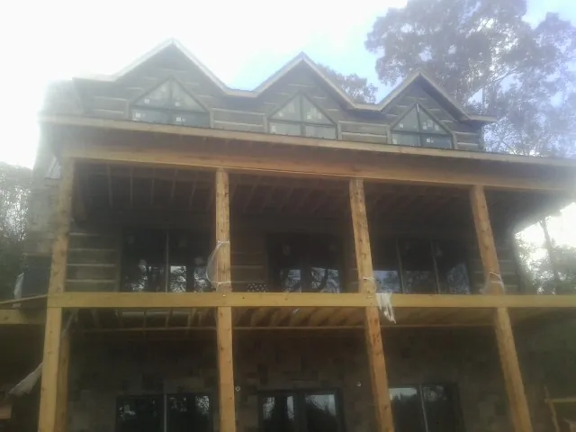 Dormers and porch framing on a large log home under construction — Roof Coating work by our crew in Ariel