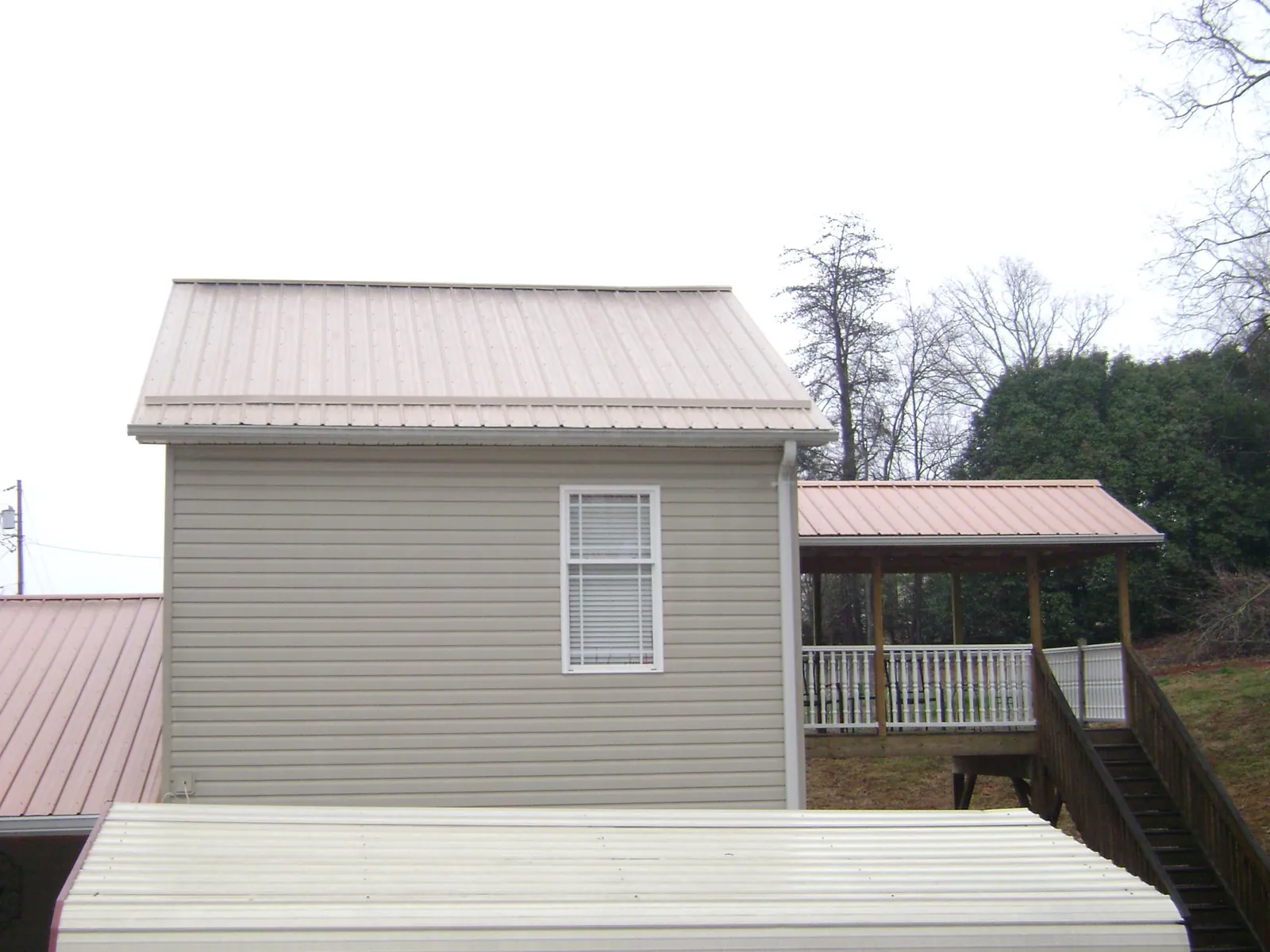 Tan metal roofs on a two story addition and attached porch, from a Roof Replacement job in Ariel