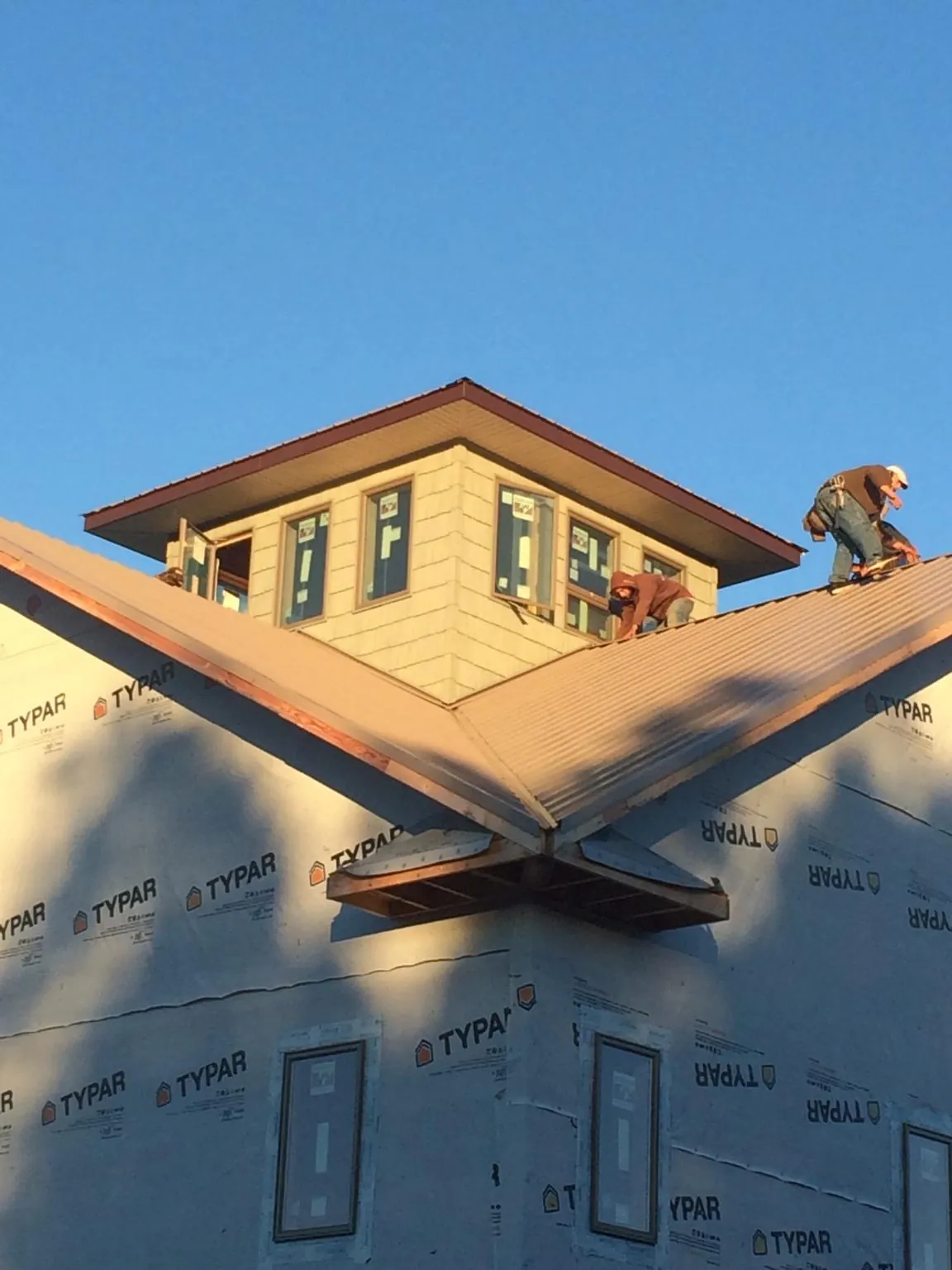 Roofers working around a rooftop cupola on a new metal roof at sunset — Roof Waterproofing in Ariel by Roofing Brothers